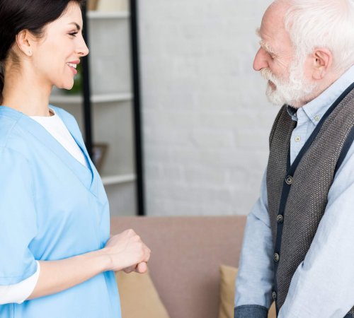 Side view of elderly man standing in room, looking at smiling doctor